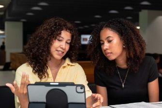 Business students studying together and sharing digital notes on a tablet.