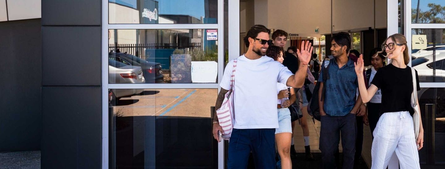 A group of students exiting a building, with two people exchanging a high-five at the entrance.