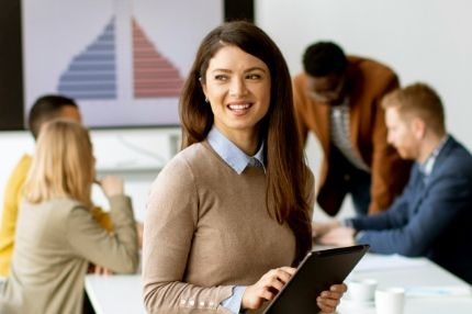 Female student using a tablet device during a data presentation meeting with colleagues in the classroom