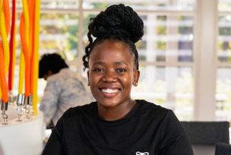 Smiling female student in a black top with a high bun hairstyle in classroom.