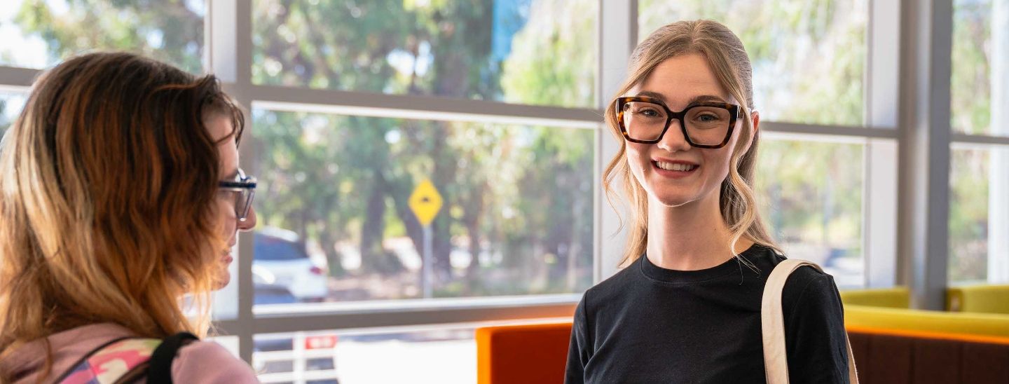Female student sitting and smiling a glass window background