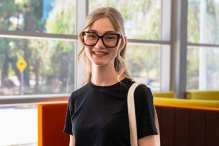 Female student sitting and smiling a glass window background