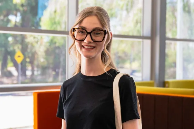 Female student sitting and smiling a glass window background