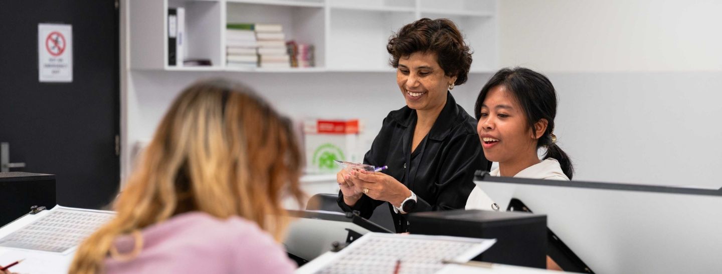 Female students discussing a project while looking at a desktop.