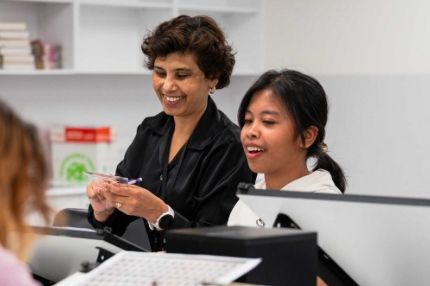 Female students discussing a project while looking at a desktop.