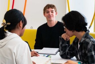 Students gathered around a table studying and talking.