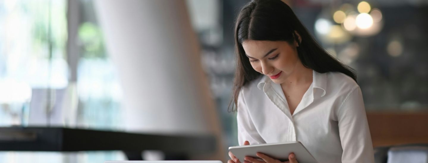 Smiling female student holding a tablet in a bright workspace