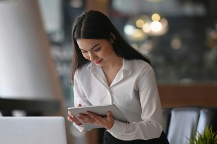 Smiling female student holding a tablet in a bright workspace