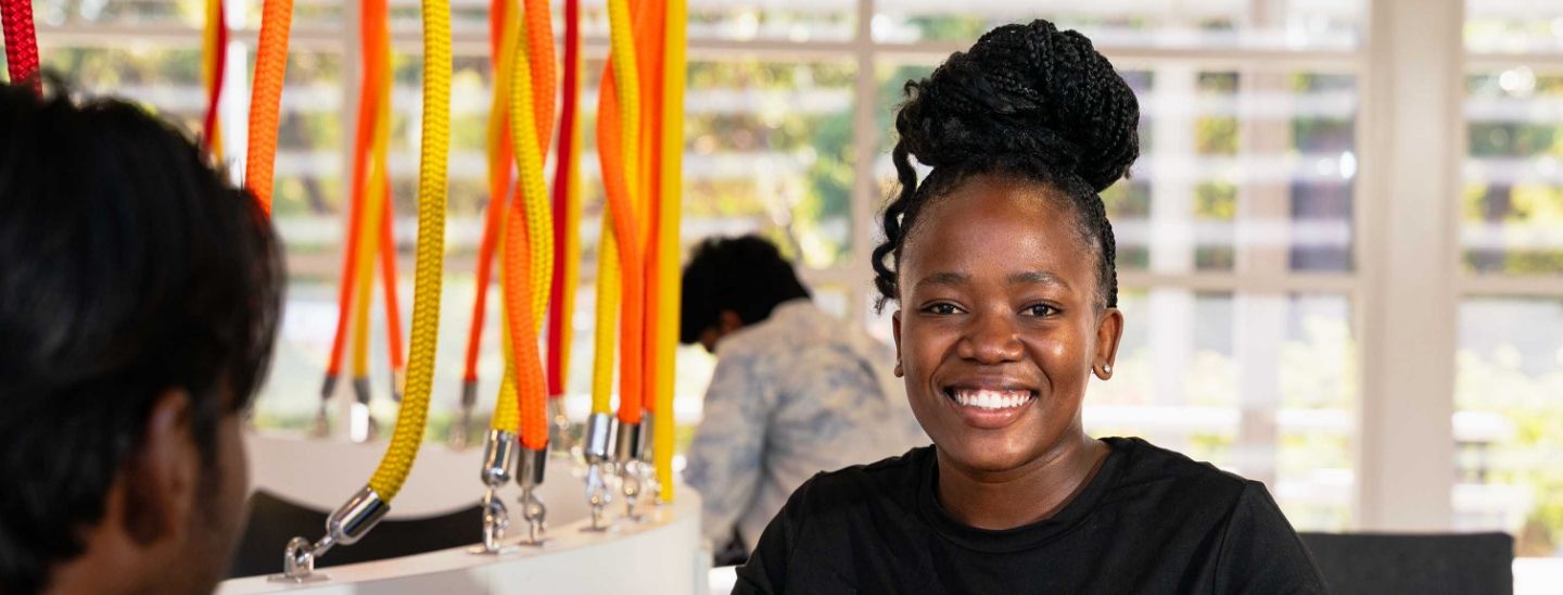 Smiling female student in a black top with a high bun hairstyle in classroom.
