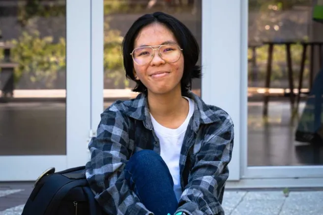 Female student sitting and smiling a glass window background