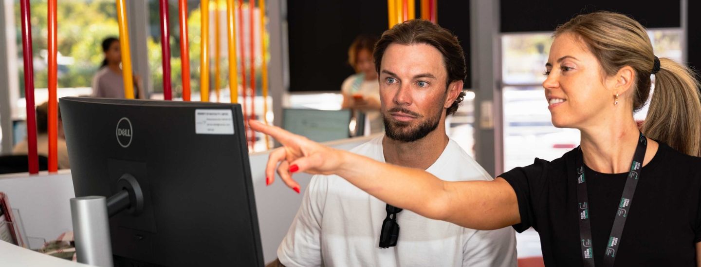 A female in a black t-shirt provides technical guidance to a colleague.