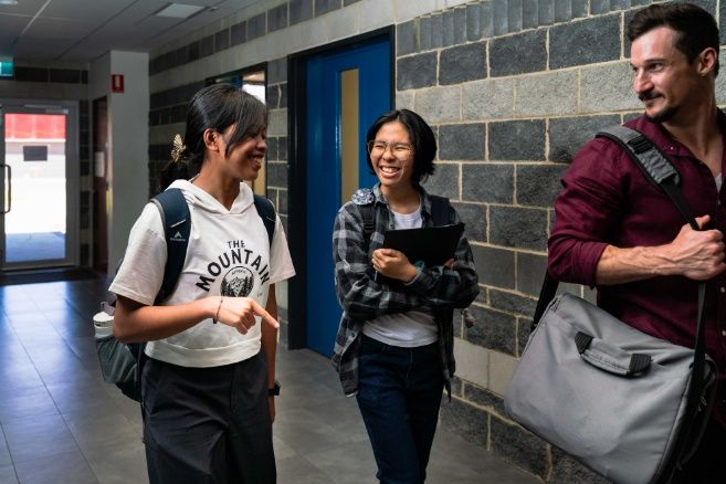 ECC college students walking and laughing together in a modern campus hallway.