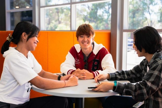 ECC students sitting around a circular white table in campus lounge.