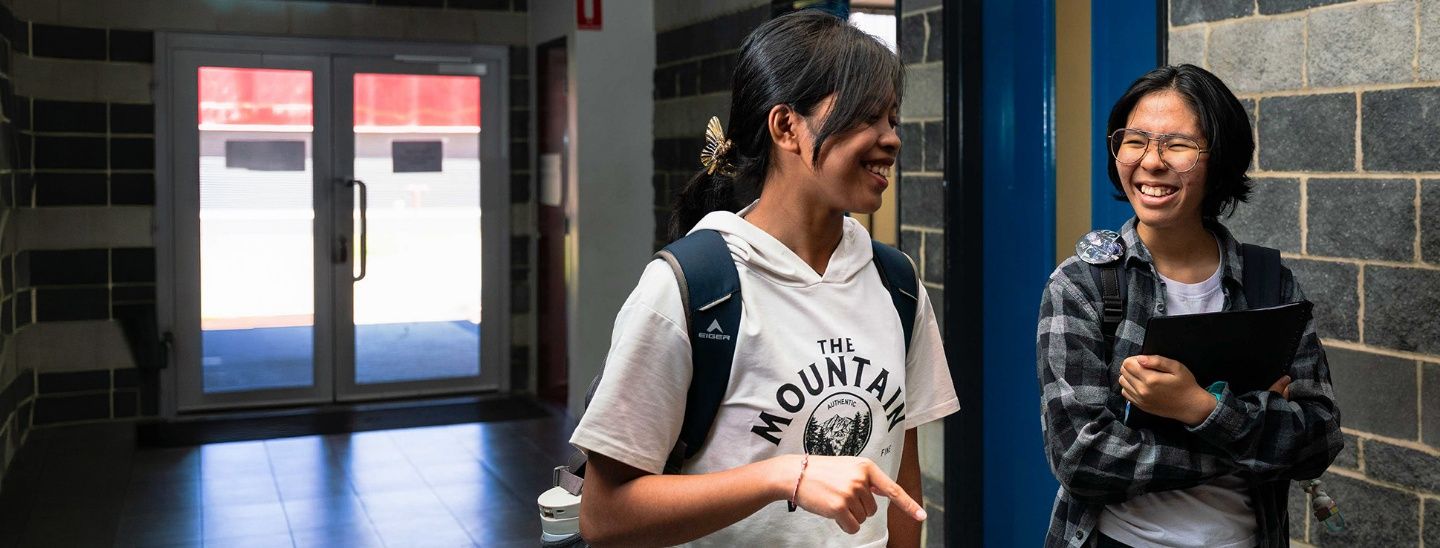 ECC college students walking and laughing together in a modern campus hallway.