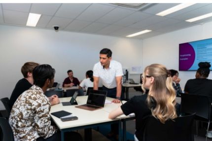 A trainer mentoring a group of teachers in a collaborative classroom environment.