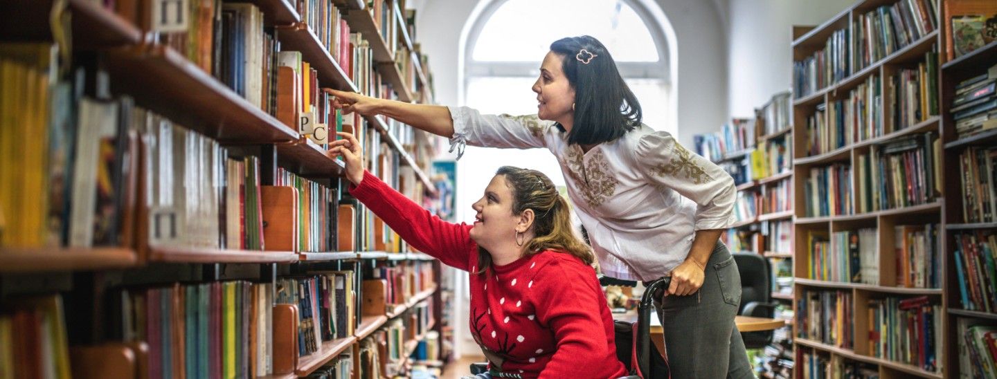 Off campus female helping student in wheelchair