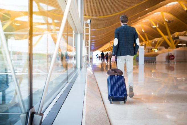Off campus male pulling suitcase in airport