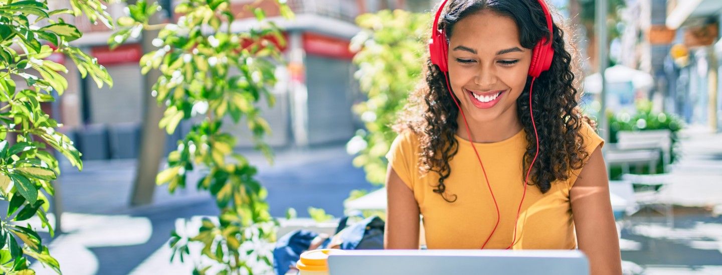 Off campus smiling female with headphones works outdoors
