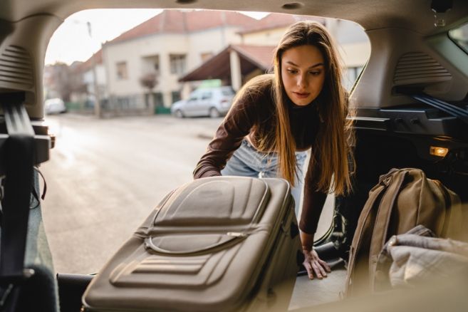 Female student packing suitcase car