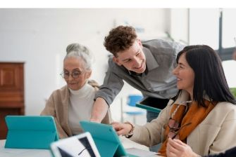 A professional team discussing work on tablets in a sunlit office.
